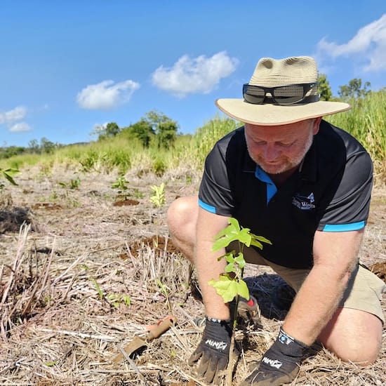 Man wearing a Tropic Wings t-shirt planting a three